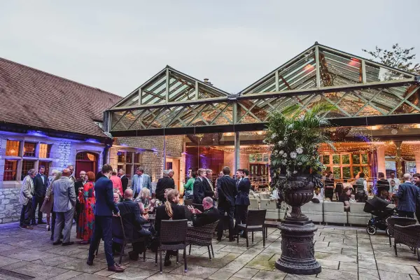 Charming outdoor venue with a spacious courtyard, glass-roofed pavilion, and elegant seating, perfect for a sophisticated celebration.