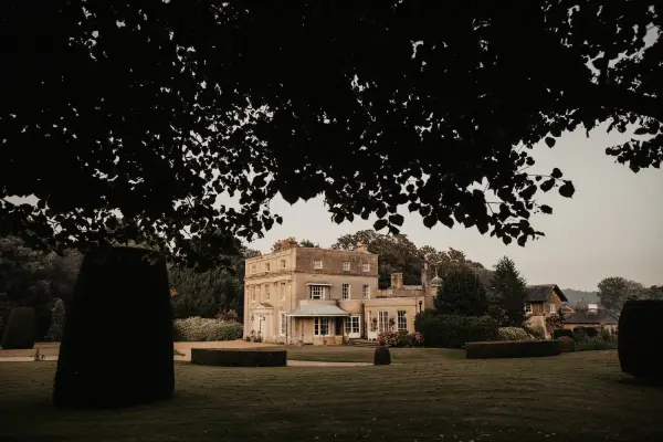 Elegant mansion surrounded by manicured gardens, framed by lush trees, creating a romantic atmosphere for outdoor ceremonies.