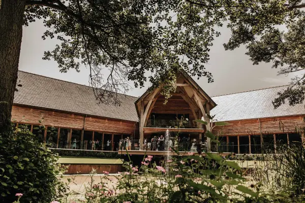A rustic wedding venue featuring a charming wooden structure surrounded by lush greenery and blooming flowers, perfect for outdoor ceremonies.
