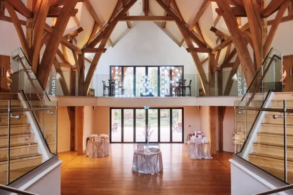 Spacious reception area featuring stunning wooden beams, glass railings, and elegant decor, perfect for a memorable wedding celebration.
