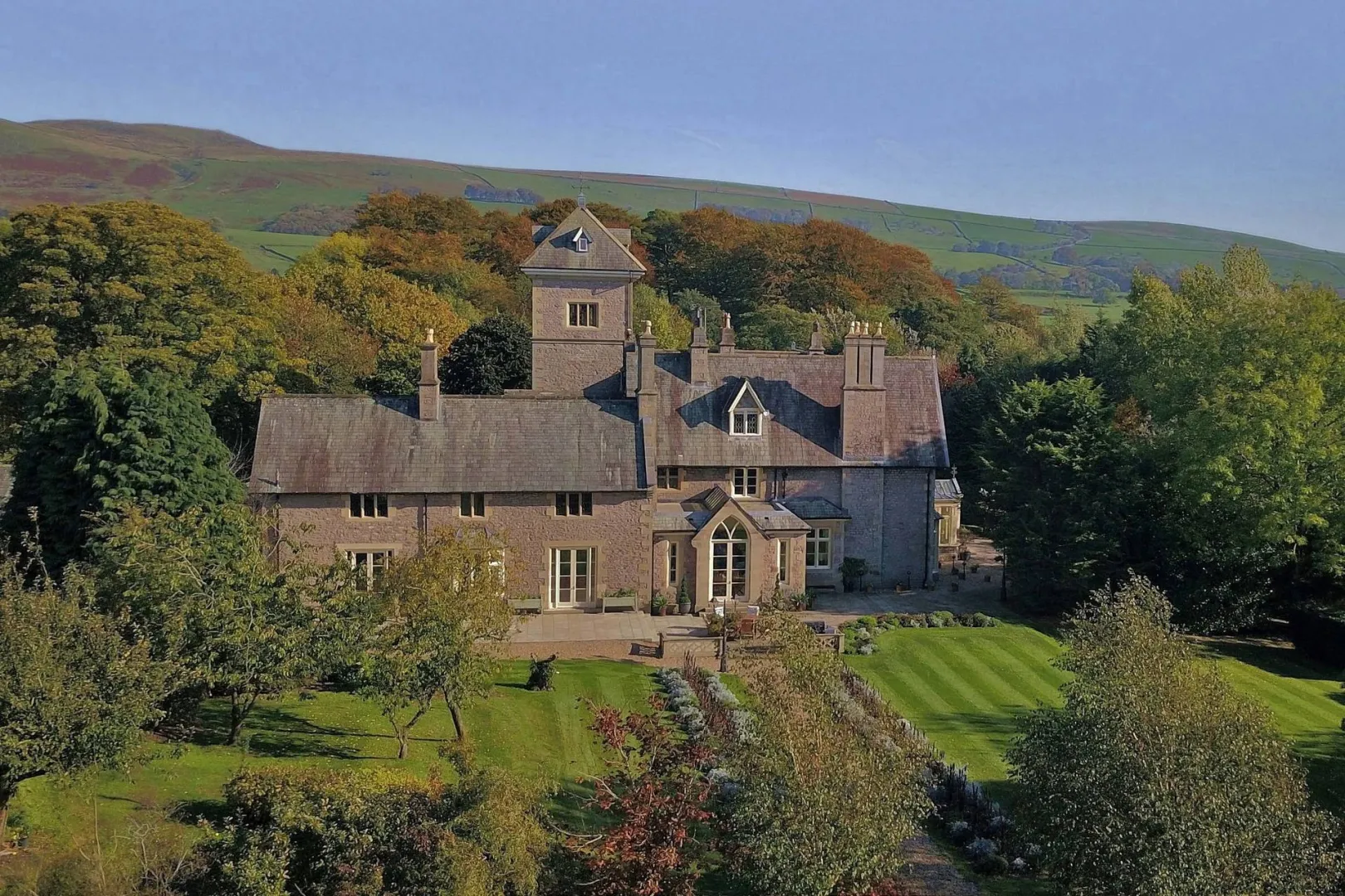 Beautiful stone manor surrounded by lush greenery, ideal for an intimate wedding. Features elegant architecture and serene landscaping.