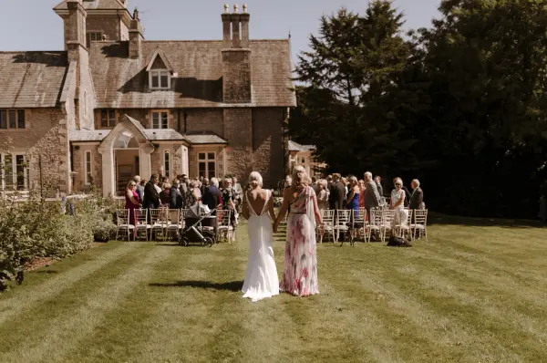 Stunning outdoor ceremony space with lush green lawn, elegant mansion backdrop, and guests seated for a joyous celebration.