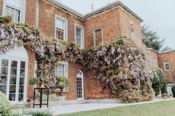 Charming brick mansion adorned with lush wisteria, ideal for romantic outdoor ceremonies and elegant receptions. Beautiful garden setting.