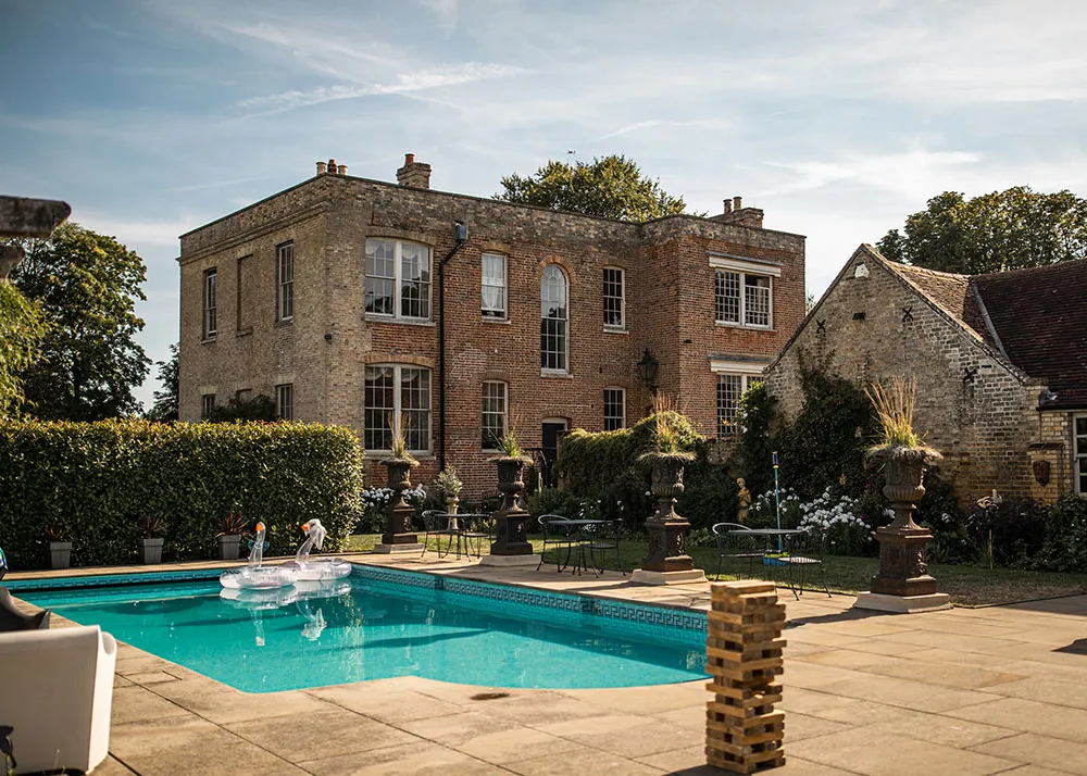 Elegant outdoor setting with a charming pool, historic brick mansion, and lush gardens perfect for a romantic wedding celebration.