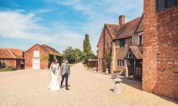 Charming rustic venue featuring a gravel path, historic brick buildings, and lush greenery, perfect for a romantic wedding day stroll.