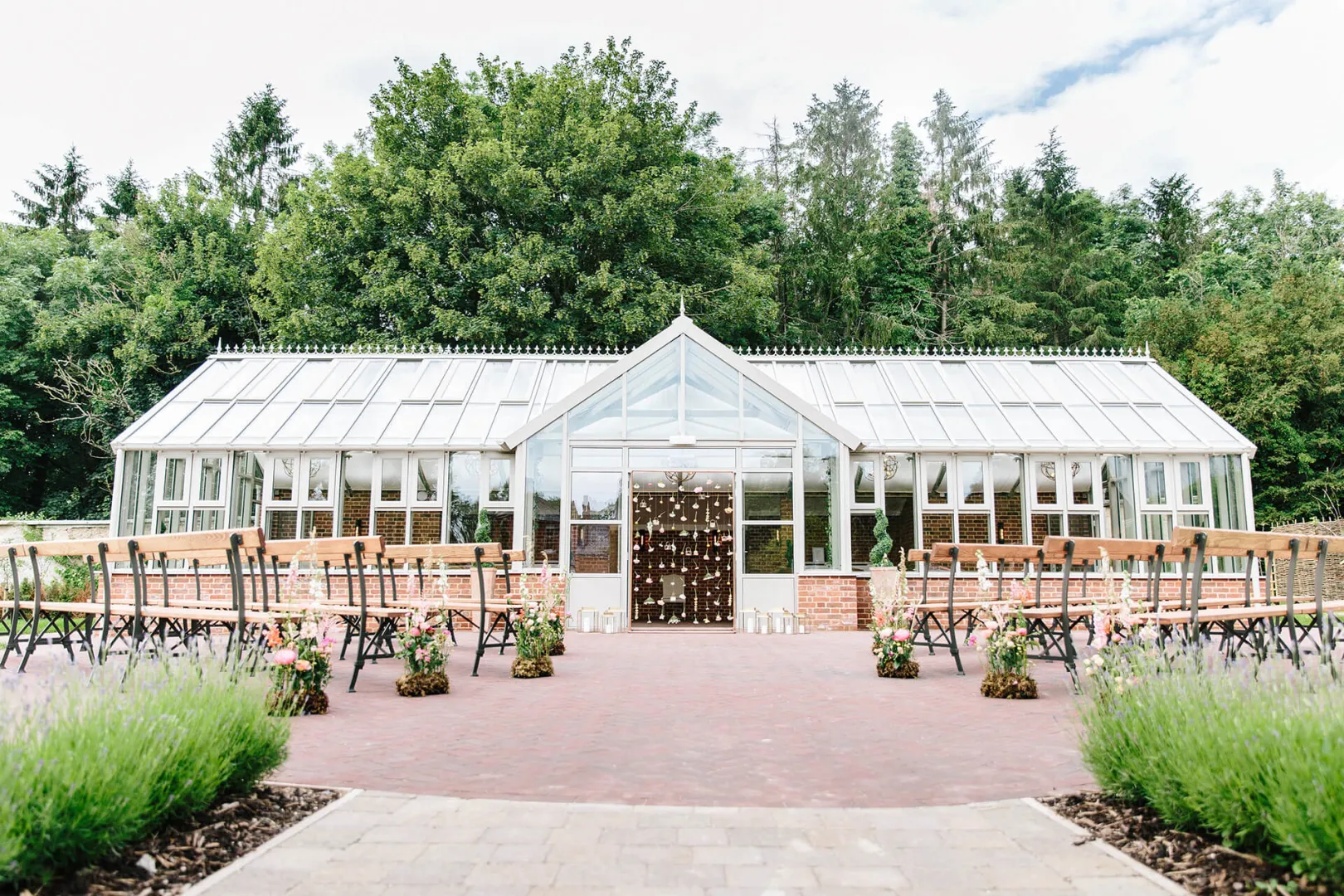 Stylish greenhouse wedding venue surrounded by lush greenery, featuring outdoor seating and charming floral accents. Ideal for intimate ceremonies.