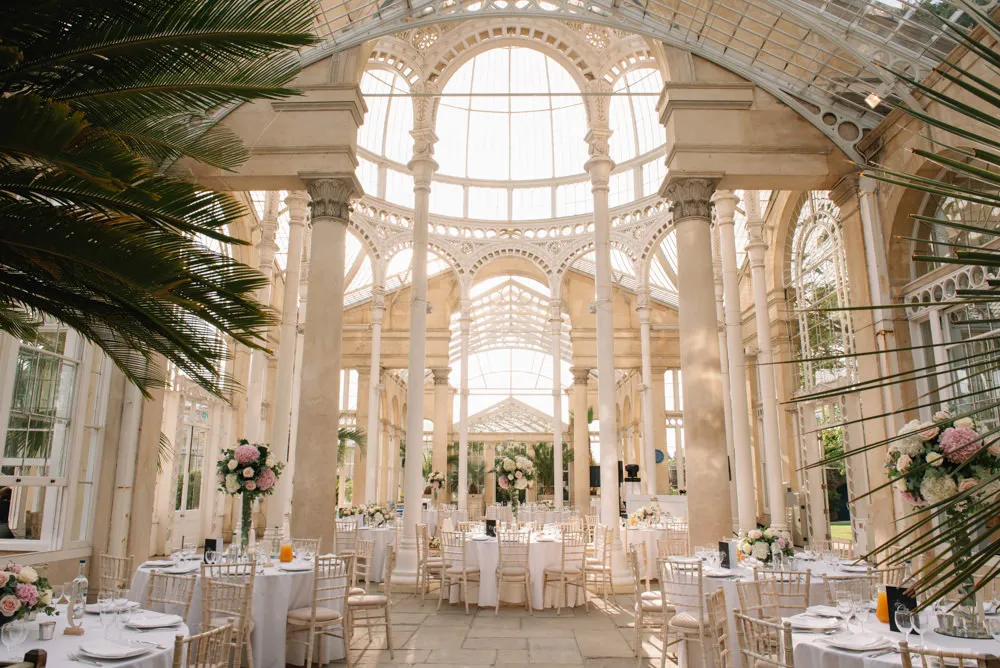Bright, airy atrium with elegant tables and lush greenery, perfect for a romantic indoor wedding reception.