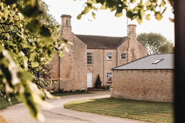 Charming rustic venue with warm brick architecture, surrounded by lush greenery and a winding pathway, perfect for wedding celebrations.