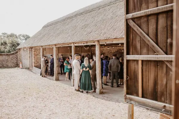 Rustic barn venue featuring a spacious outdoor area, ideal for mingling guests dressed in elegant attire, surrounded by natural scenery.