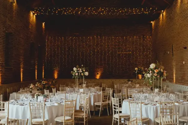 Rustic brick venue featuring elegantly arranged tables, soft lighting, and floral centerpieces, perfect for a romantic wedding celebration.