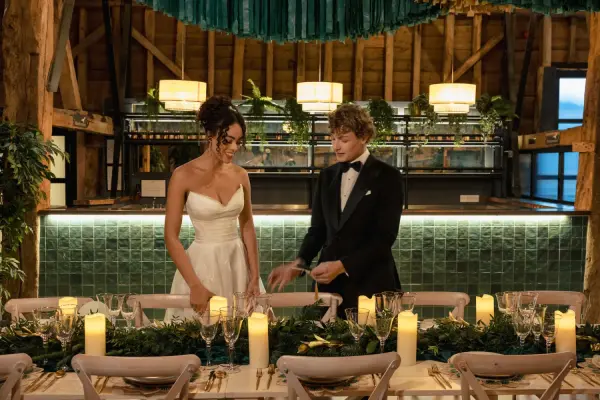 Intimate reception setting with wooden beams, elegant greenery, candlelit tables, and a cozy bar backdrop perfect for a romantic celebration.