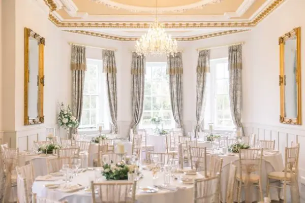 Elegant ballroom adorned with crystal chandeliers, white drapes, and decorated tables, creating a romantic ambiance for weddings.