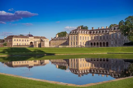 Grand estate featuring a stunning reflection in a serene pond, surrounded by lush green lawns and a picturesque sky. Perfect for elegant ceremonies.