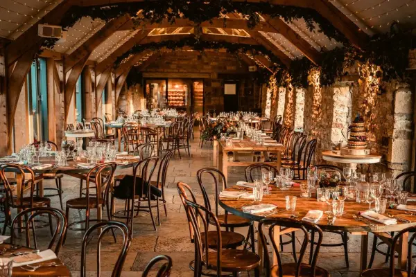 Charming rustic barn venue featuring elegantly set wooden tables, warm lighting, and lovely floral decor for a romantic wedding celebration.