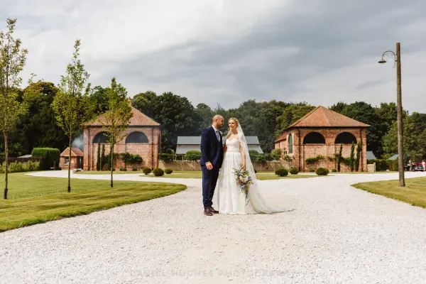 Charming rustic venue featuring a gravel pathway, lush landscaping, and intimate architecture, perfect for outdoor wedding celebrations.