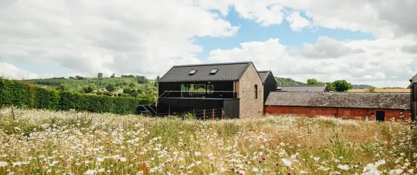 Charming rustic venue amidst wildflower fields, featuring modern architecture and scenic views, perfect for outdoor ceremonies.