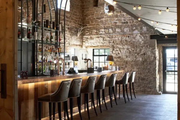 Rustic bar area featuring sleek seating, exposed stone walls, and warm lighting, perfect for cocktail hour at a wedding celebration.