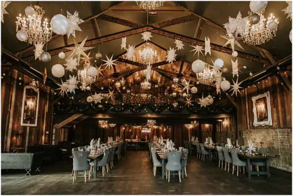 Elegant banquet hall featuring dramatic chandeliers, festive decor, and rustic wooden walls, perfect for a romantic wedding reception.
