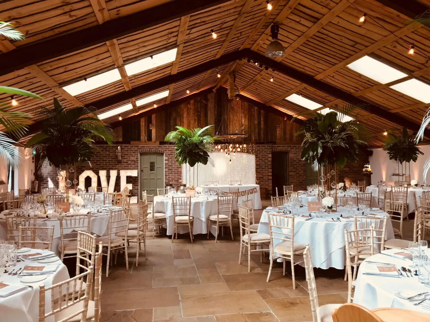 Charming rustic barn with elegant dining setup, lush greenery, and warm lighting, perfect for intimate weddings and celebrations.