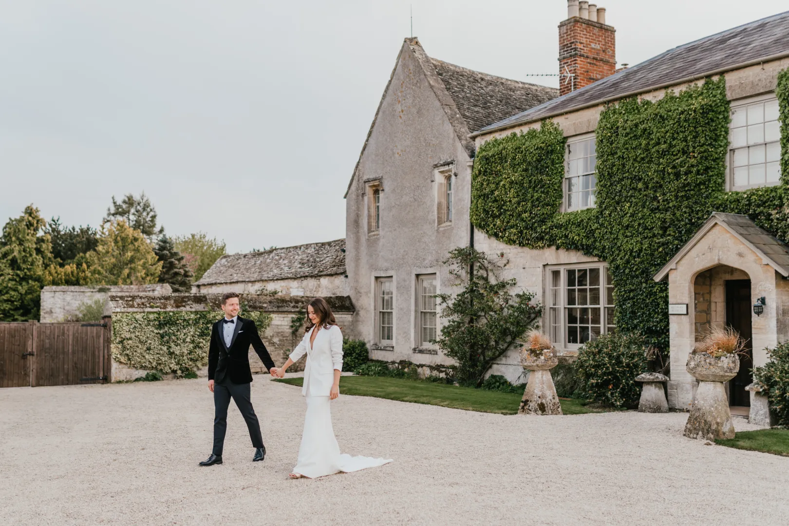 Charming outdoor walkway leading to a historic stone house, surrounded by lush greenery, perfect for intimate wedding celebrations.