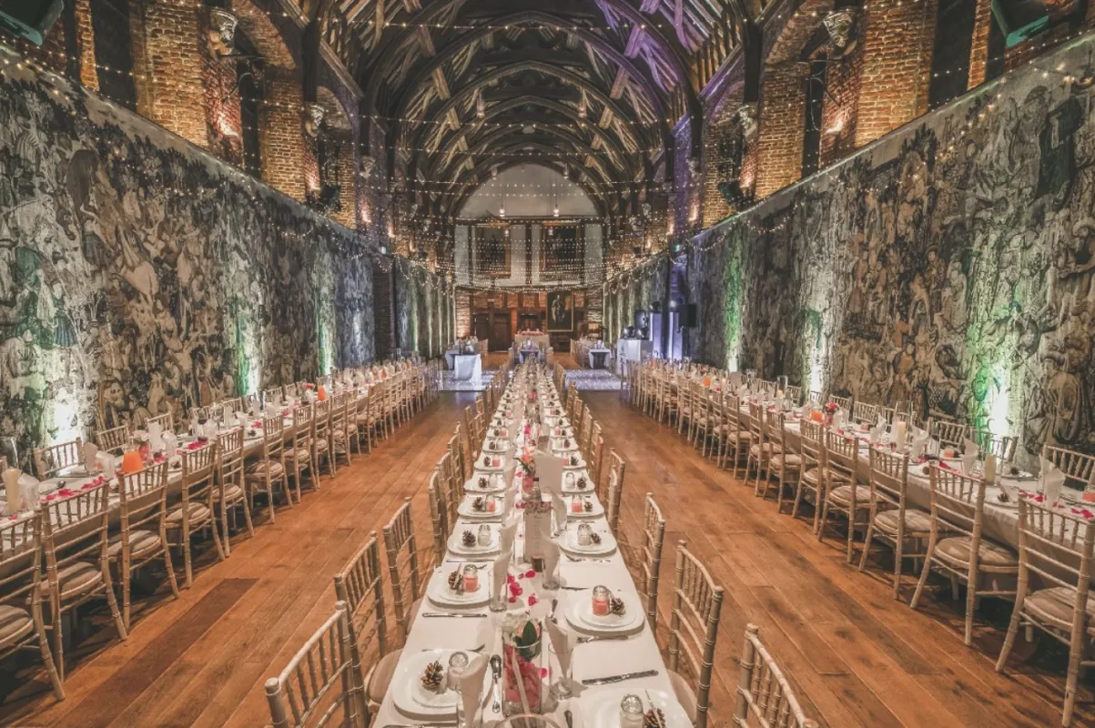 Stylish reception hall featuring long banquet tables, exposed brick walls, and dramatic lighting, perfect for a memorable wedding celebration.
