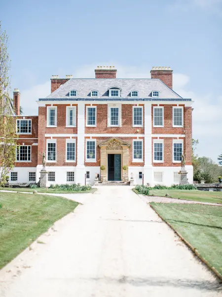 Imposing historic manor with elegant architecture, a grand entrance, and lush green landscaping, ideal for a sophisticated wedding celebration.