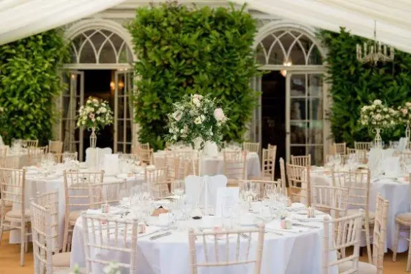 Elegant indoor reception with lush greenery, decorated tables, and crystal centerpieces, creating a romantic and inviting atmosphere.