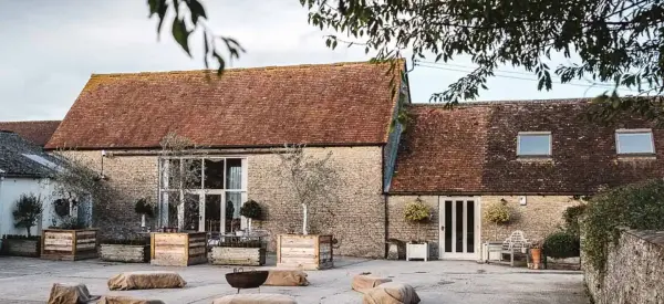 Charming rustic barn with a weathered roof, surrounded by landscaped gardens and cozy outdoor seating for intimate gatherings.