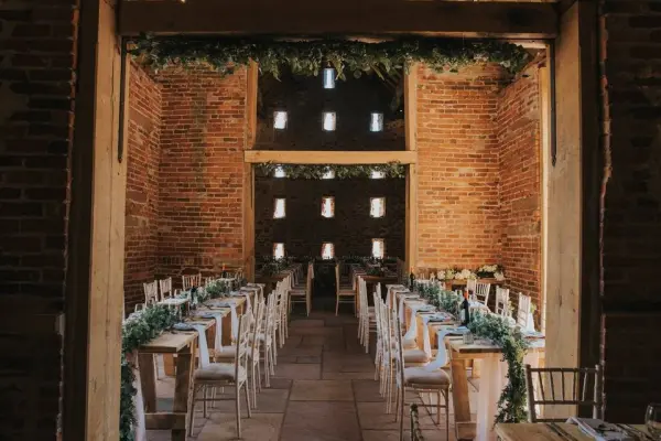 Rustic wedding venue featuring exposed brick walls, long wooden tables, and greenery accents, creating a warm, inviting atmosphere.