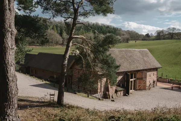 Charming rustic barn surrounded by lush green fields, ideal for serene outdoor ceremonies and intimate celebrations.