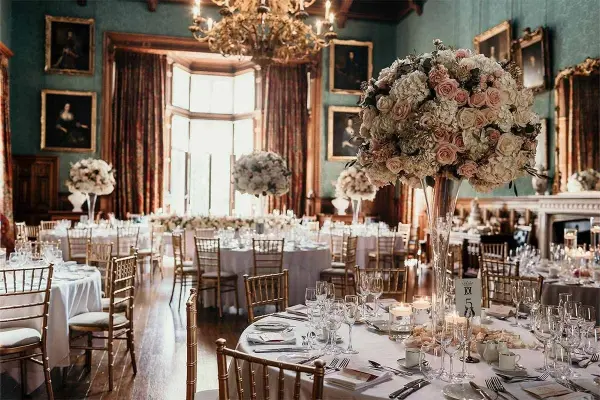 Elegant ballroom adorned with lush floral centerpieces, classic decor, and golden chandeliers, creating a romantic atmosphere for weddings.