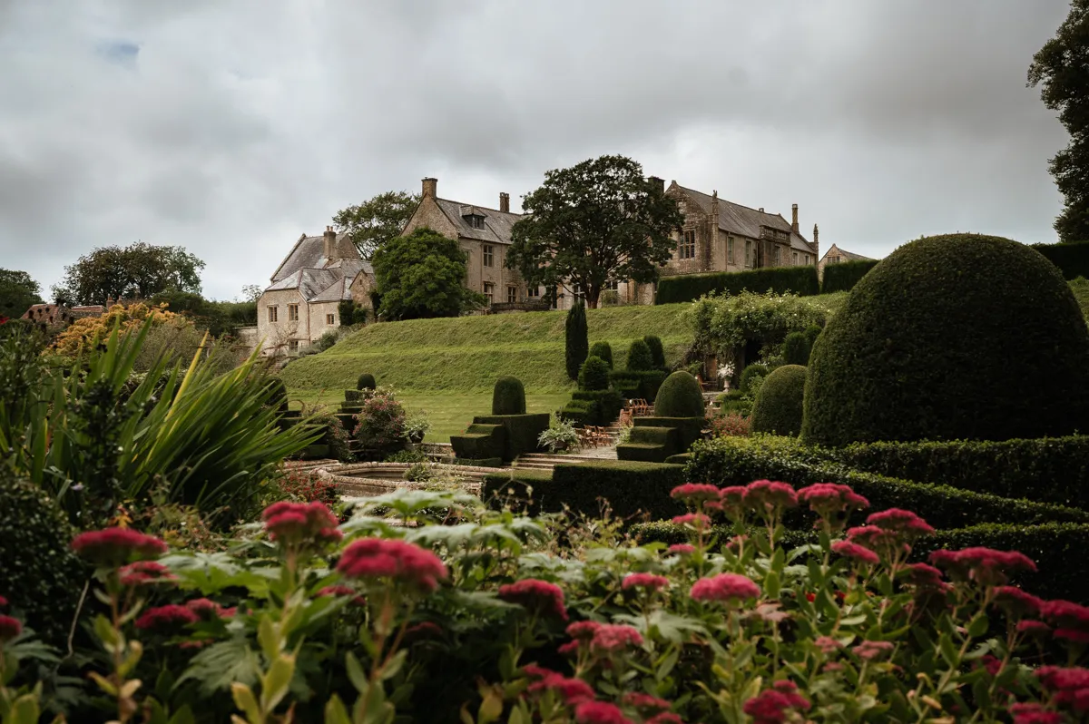 Lush gardens filled with vibrant flowers surround a charming estate, offering a serene backdrop for outdoor ceremonies and intimate gatherings.