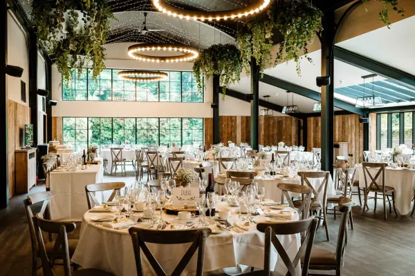 Elegant reception space featuring round tables, lush greenery, and large windows, creating a bright and inviting atmosphere for celebrations.
