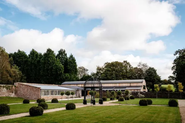 Spacious landscaped lawn featuring a charming gazebo and modern indoor venue, surrounded by lush greenery and neatly trimmed hedges.