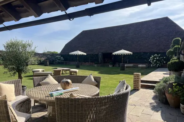 Charming outdoor ceremony space with rustic barn, cozy seating, and lush greenery, perfect for an intimate wedding gathering.