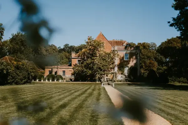 Lush green lawns lead to a charming historic house, surrounded by serene gardens, perfect for outdoor ceremonies and elegant receptions.