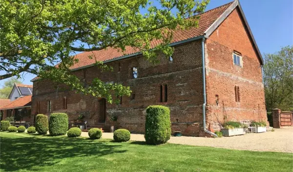 Charming rustic barn surrounded by manicured lawns and sculpted hedges, perfect for an outdoor or indoor wedding celebration.