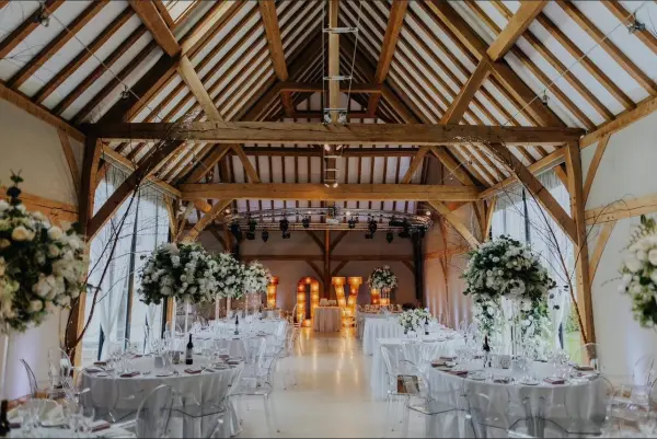 Rustic barn venue featuring exposed beams, elegant floral arrangements, and stylish table settings for a charming wedding reception.