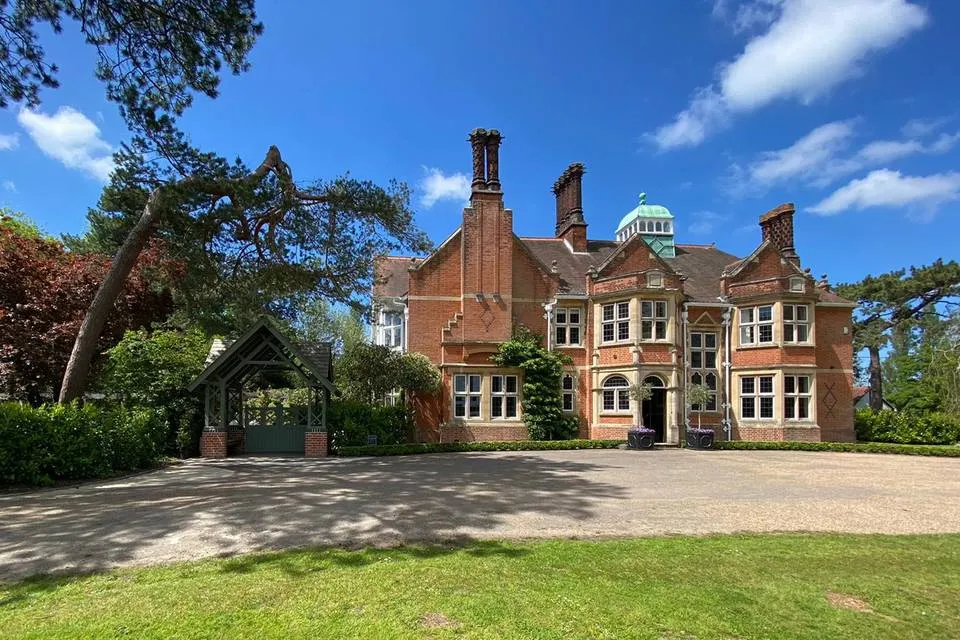 Stunning red brick mansion with elegant architecture, surrounded by lush greenery and a spacious outdoor area for wedding festivities.