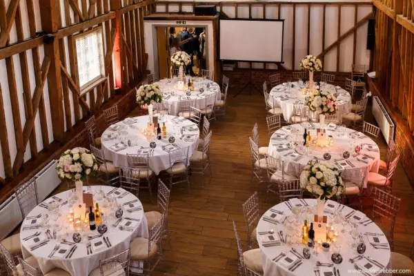 Charming rustic barn venue featuring elegant round tables adorned with floral centerpieces and warm lighting, perfect for a wedding reception.