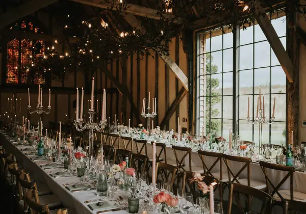 Elegant rustic barn interior with long reception tables, candles, and large windows showcasing scenic views. Perfect for intimate weddings.
