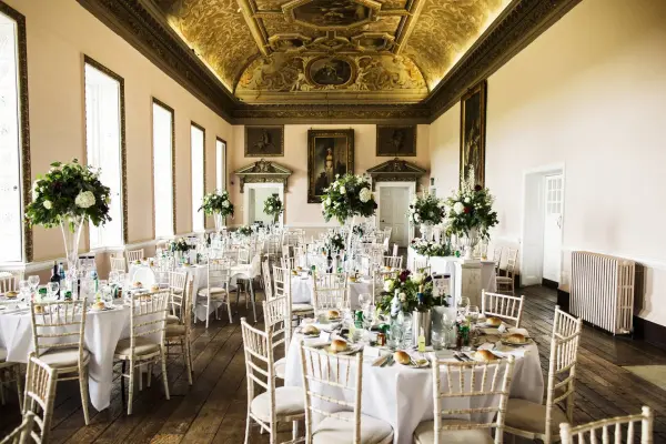 Elegant ballroom featuring ornate ceilings, large windows, and beautifully arranged tables adorned with floral centerpieces and fine dining.