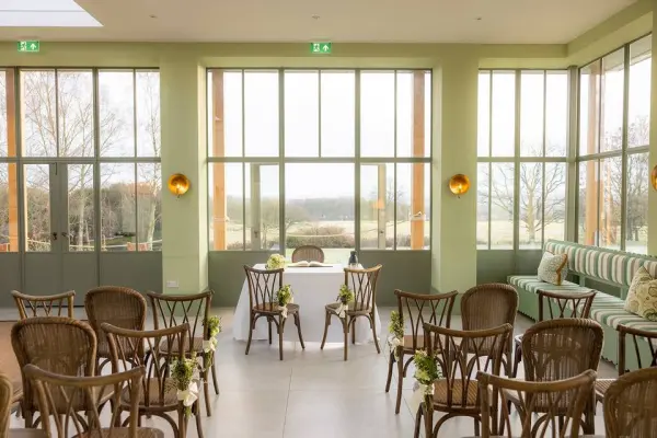 Bright and airy indoor ceremony space features elegant decor, wooden chairs, and panoramic views, perfect for intimate weddings.