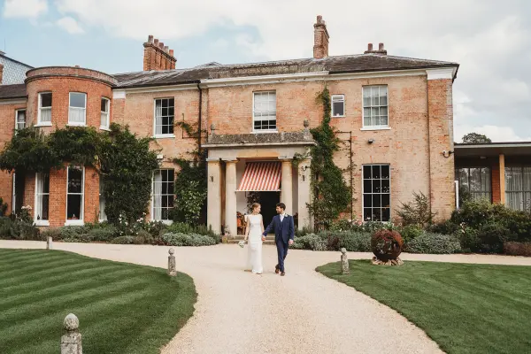 Charming brick mansion with lush gardens, perfect for outdoor ceremonies and intimate wedding celebrations. Pathway leads to the elegant entrance.