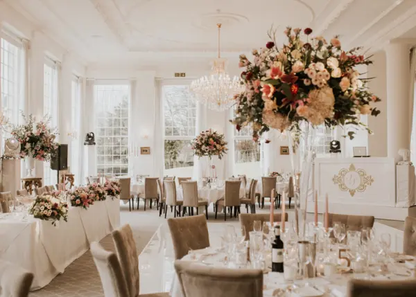 Elegant reception space featuring tall floral centerpieces, soft lighting, and large windows for a romantic wedding atmosphere.