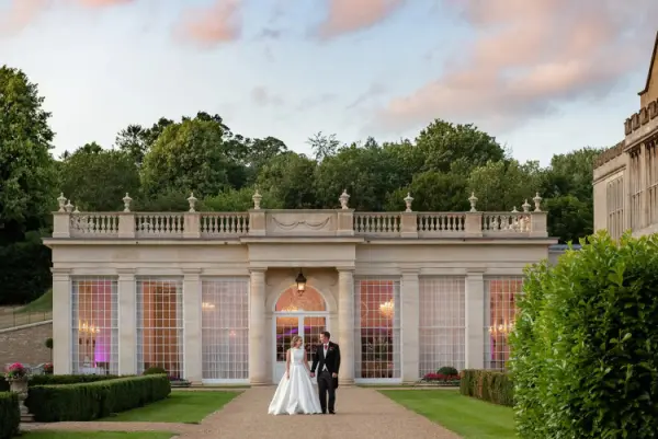 A stunning stone pavilion with large windows, surrounded by lush greenery, perfect for elegant outdoor ceremonies and receptions.