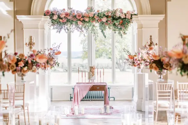 A stunning indoor ceremony space featuring elegant floral arrangements, a decorated altar, and soft natural light streaming through large windows.