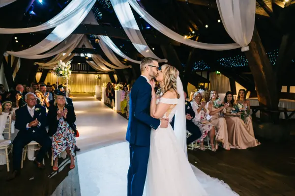 A romantic indoor ceremony in a rustic barn, featuring exposed beams, soft drapes, and a cozy ambiance with attentive guests.