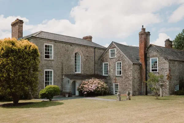 Charming stone mansion surrounded by lush greenery, perfect for outdoor ceremonies and intimate receptions in a picturesque setting.