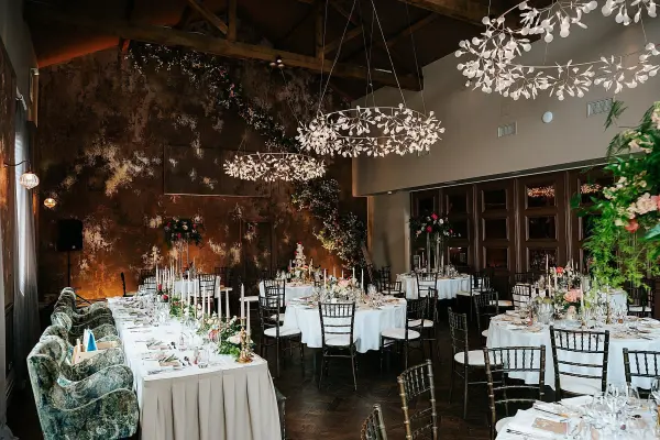 Intimate reception space featuring elegant tables, lush floral arrangements, unique hanging lights, and a warm, inviting atmosphere.